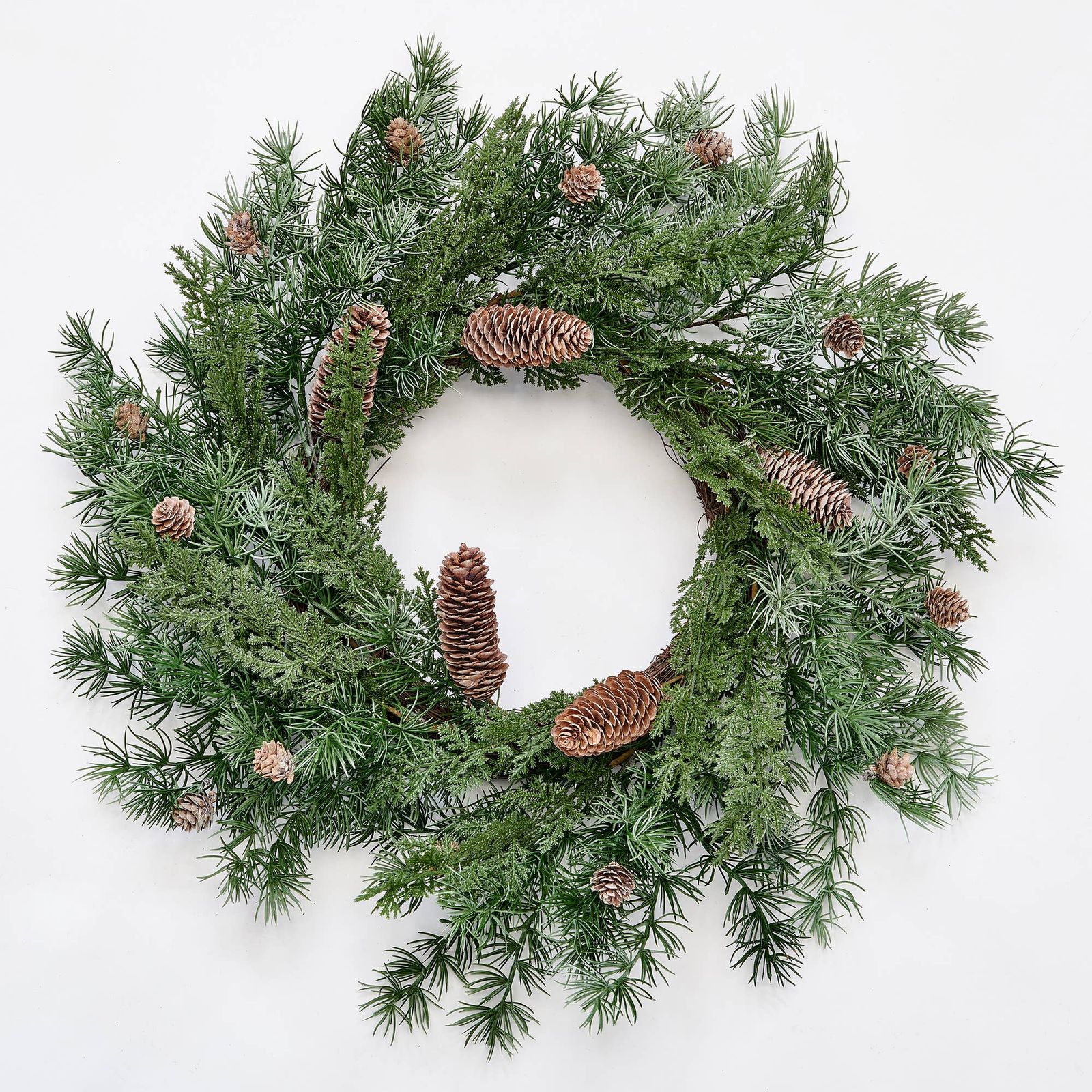 Twenty-four inch faux pine wreath with layered evergreen textures and natural pine cones, photographed flat on white